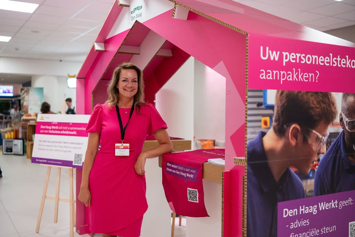 Roze huis van karton op een event met vrouw ervoor